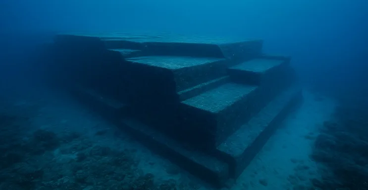 Formación rocosa sumergida del Monumento de Yonaguni, con plataformas escalonadas y ángulos rectos bajo el océano, rodeada de aguas cristalinas.