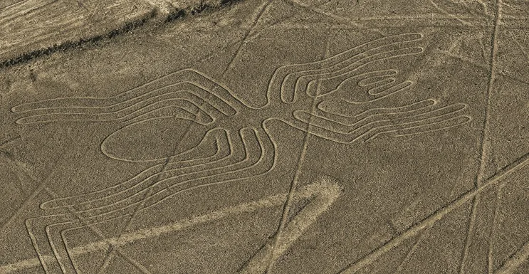 Vista aérea de las Líneas de Nazca en el desierto peruano con figuras de colibrí y mono bajo luz dorada